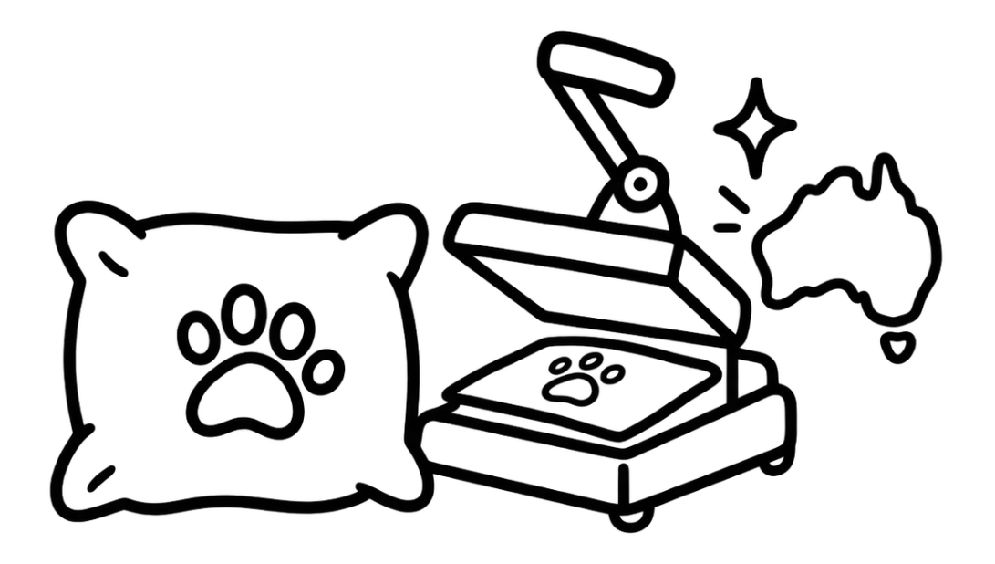 Black and white line art icon depicting a pet paw print pillow next to a hot air stamping iron with a paw print on the plate, with a small silhouette of Australia and sparkles.