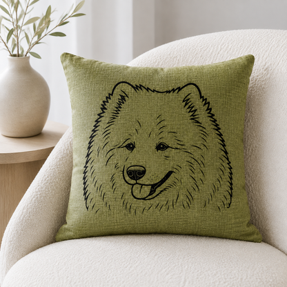 An olive green throw pillow with a black line art illustration of a fluffy dog face, resting on a cream-colored armchair next to a wooden side table with a vase.