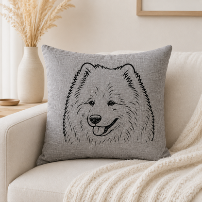 A square grey throw pillow with a black line art illustration of a fluffy dog face, resting on a cream-colored sofa with a knit blanket.