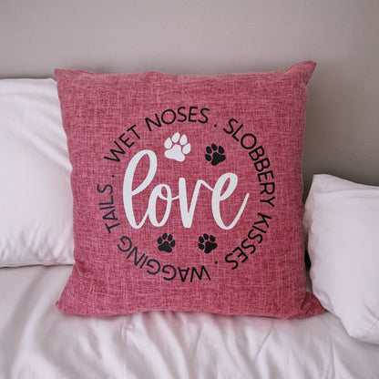 A pink cushion cover with the word 'love' and dog-related phrases such as 'wagging tails', 'wet noses', and 'slobbery kisses' printed on it, along with paw prints.  - dog gift in Australia made by Rieko's World.