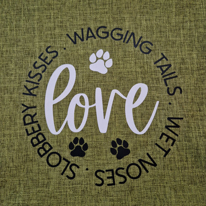 A green cushion cover with the word 'love' and dog-related phrases such as 'wagging tails', 'wet noses', and 'slobbery kisses' printed on it, along with paw prints  - dog gift in Australia made by Rieko's World.