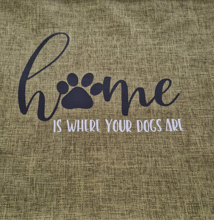 A close up of a green cushion cover with the text 'Home is Where Your Dogs Are' and a paw print design - dog gift, Australia by Rieko's World