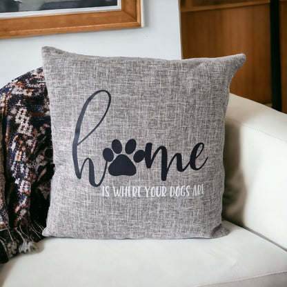 A grey cushion cover with the text 'Home is Where Your Dogs Are' and a paw print design on a sofa - dog gift, Australia by Rieko's World