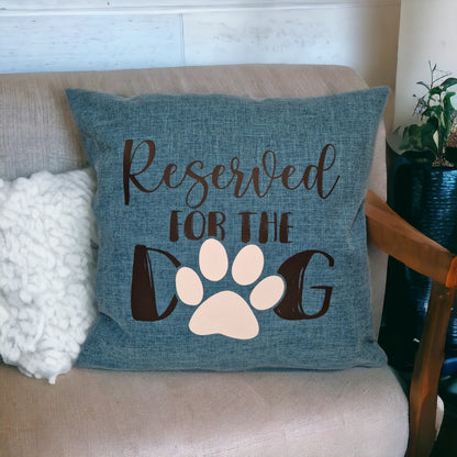 A close up of a blue cushion cover on tan sofa with white fluffy cushion with 'Reserved for the Dog' text and a paw print design made in Australia by Rieko's World.